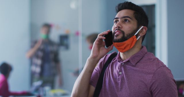 Man Talking on Phone with Mask Below Chin in Modern Office - Download Free Stock Images Pikwizard.com