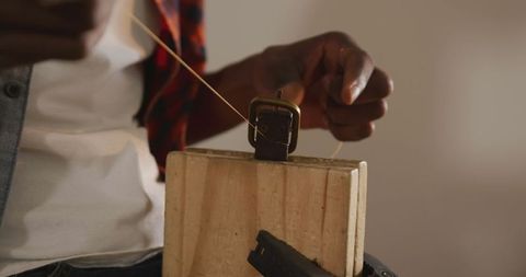 Skilled leather craftsman working on belt in workshop
