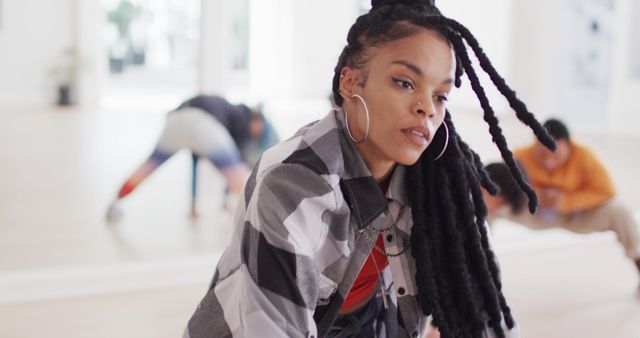 Young woman with braided hair engaging in a group fitness class. Ideal for exercise, health, lifestyle, and determination concepts. Can be used for promoting fitness programs, health and wellness products, or motivational content.