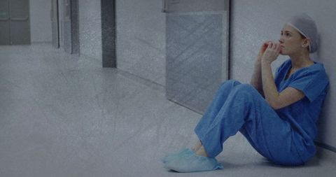 Exhausted Nurse Sitting Alone in Hospital Corridor