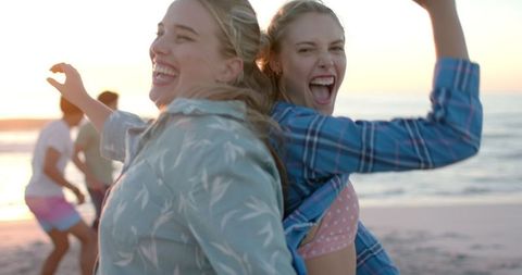 Young Women Laughing Joyfully at Beach Party Sunset