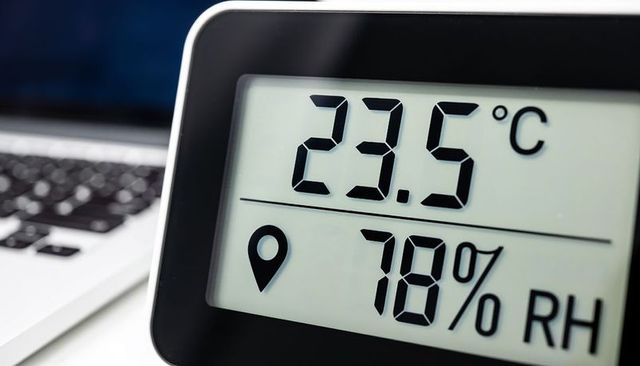Digital thermo-hygrometer displaying 23.5°c and 78% rh on white desk with laptop