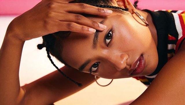 Reclining woman meeting camera gaze with braided hair, hoop earrings and striped top