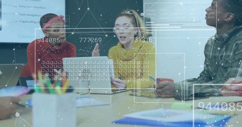 Presenting leader in mustard knit holding phone while team collaborating with data overlays