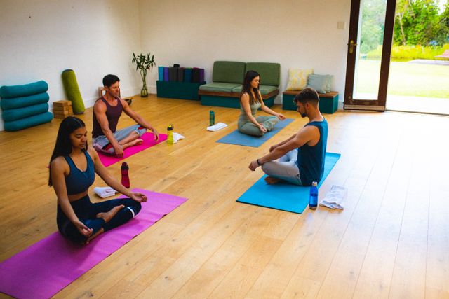Caucasian male instructor teaching meditation to multiracial men and woman in yoga studio. unaltered, fitness, yoga and healthy lifestyle.