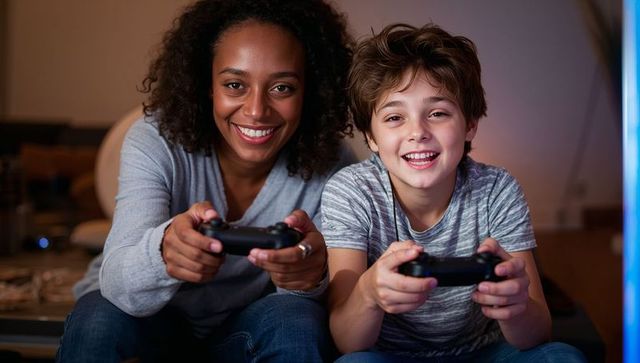 Smiling mom and son playing console games together on couch, cozy family gaming night