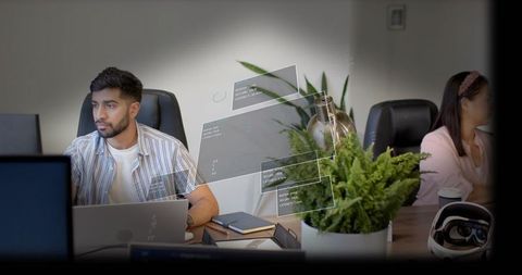 Young professional working at laptop with augmented hud overlay in modern coworking office