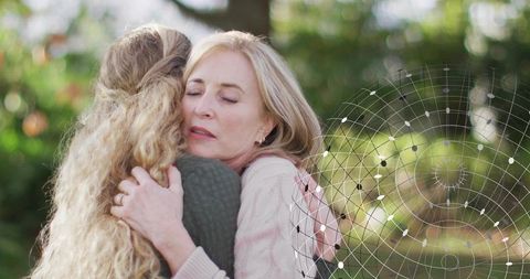 Mother and daughter embracing comforting hug in garden with geometric network overlay and bokeh