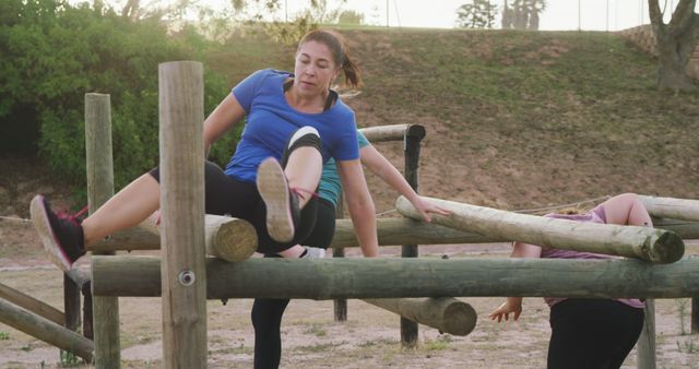 Determined caucasian woman climbing over obstacle at bootcamp fitness training course. Female fitness, challenge and healthy lifestyle.