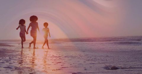 Walking at sunset with kids holding hands on beach silhouette reflection barefoot family