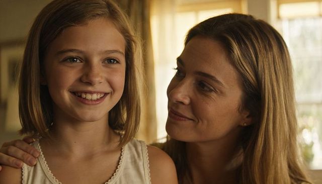 Smiling mother sharing warm moment with daughter, tender parent child bond at home