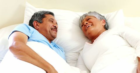 Senior Latino Couple Laughing Together in Bed