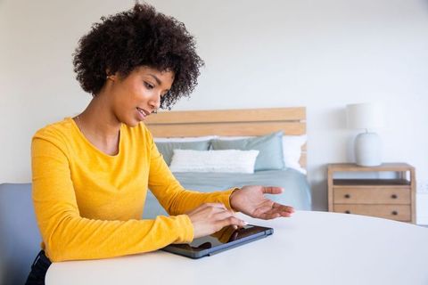 Relaxed Woman in Mustard Top Using Tablet in Cozy Bedroom Setting