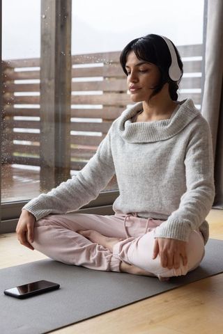 Woman Meditating in Cozy Home with Headphones for Relaxation