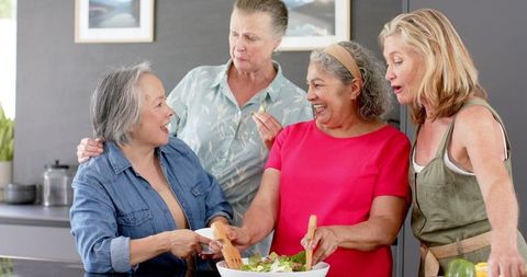 Senior Women Friends Joyfully Preparing Salad in Kitchen