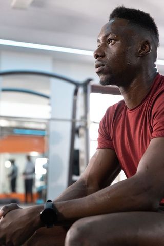 African american athlete pausing to catch breath after intense gym workout, recovery