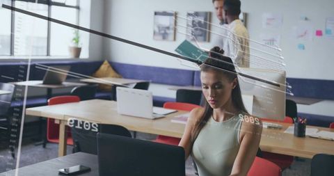 Focused woman working on laptop in modern coworking space
