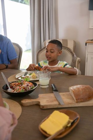 Young boy enjoying family meal with salad and bread