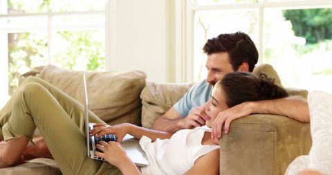 Happy Couple Relaxing on Sofa with Son Engaged in Digital Play