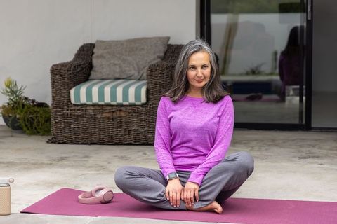 Mature woman practicing mindful meditation and yoga on patio, outdoor wellness lifestyle