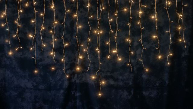 Warm White Fairy Lights Hanging in Vertical Strands on Dark Backdrop for Event Decor