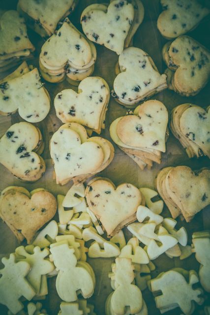 Heart-shaped cookies with chocolate chips are displayed in a charming and rustic arrangement. Ideal for use in baking blogs, food magazines, recipe websites, advertisements for bakeries, or social media posts celebrating homemade treats and baking creativity.