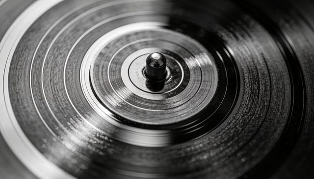 Macro close-up showing grooved vinyl record on turntable spindle monochrome texture