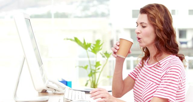 Woman Working at Computer and Drinking Coffee in Well-Lit Office - Download Free Stock Images Pikwizard.com