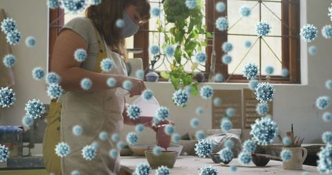 Masked Artist Working in Pottery Studio with Digital Virus Overlay
