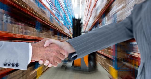 Digital composite of Cropped image of business people doing handshake in warehouse