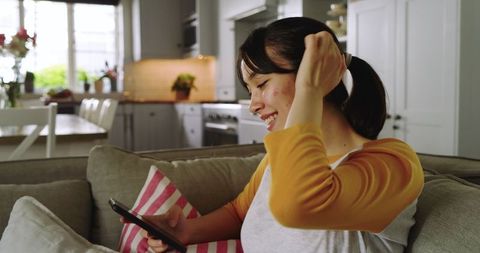 Young Woman Relaxing at Home with Smartphone and Headphones