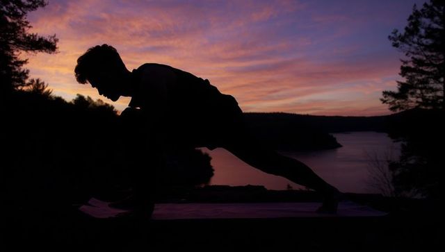 Silhouette of Athlete Doing Lunge Stretch by Lakeside at Sunset
