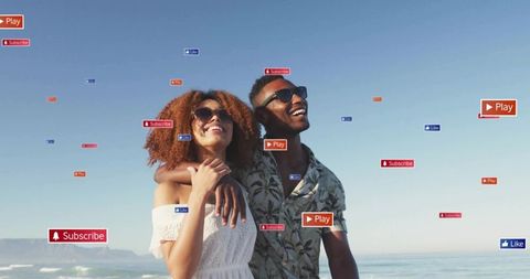 Smiling couple on beach with social media play, subscribe and like icons floating overhead