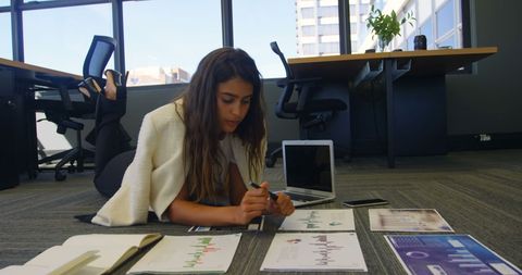 Businesswoman analyzing financial reports on office floor