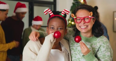 Cheerful friends celebrating at festive holiday party wearing reindeer glasses