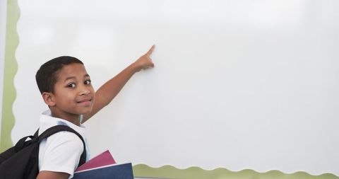 Young Student Pointing at Blank Whiteboard