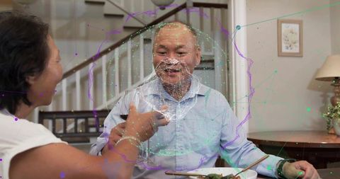 Mature chinese couple using smartphone at dining table with augmented reality overlay