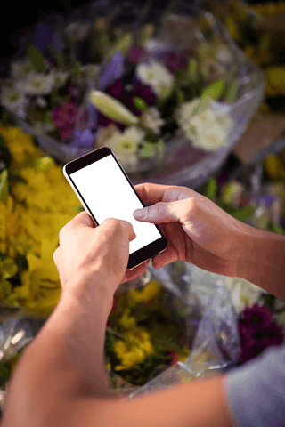 Man interacting with smartphone at vibrant flower shop