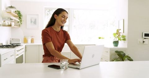 Business Woman Typing on Laptop in Bright Minimalist Kitchen