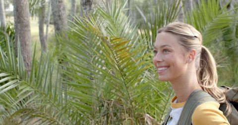 Young Woman Smiling Outdoors Surrounded by Lush Greenery