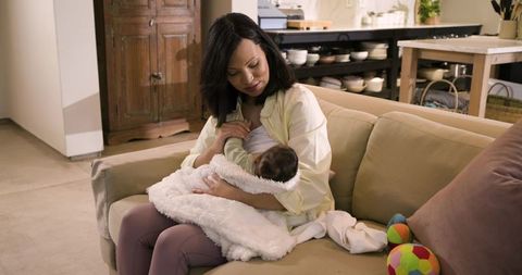 Mother Breastfeeding Infant on Cozy Couch at Home