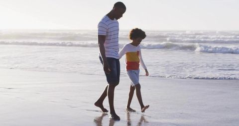 Father and Son Strolling Along Ocean Shoreline at Sunset