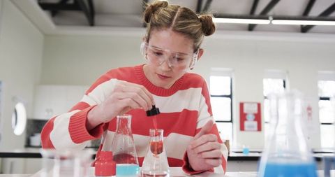 Young Scientist Conducting Experiments with Red Solution in Laboratory