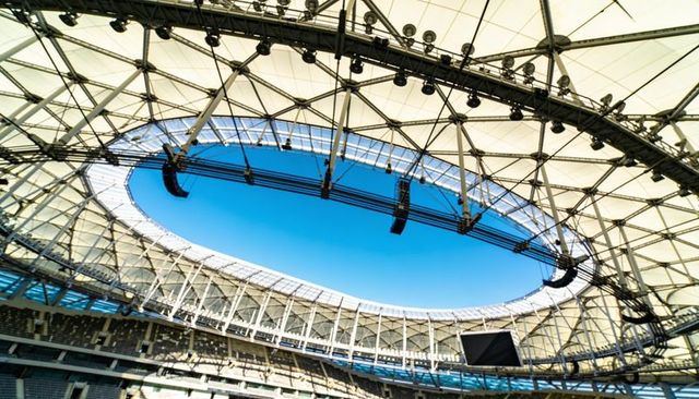 Oval stadium roof opening framing canopy and steel truss structure with suspended lighting