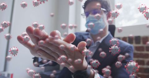 Man in office using hand sanitizer among floating coronavirus cells
