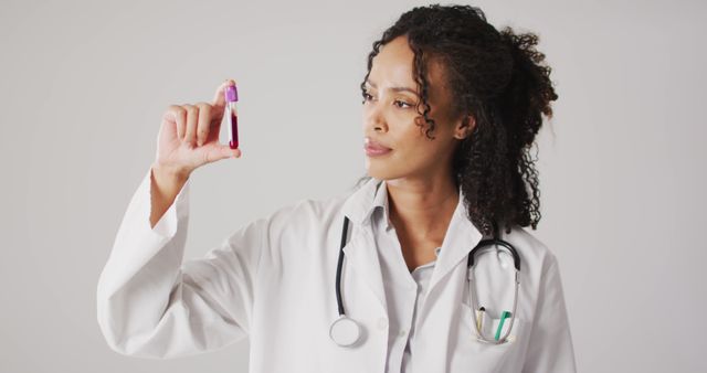 Image of biracial female doctor holding test tube on white background. global medicine and healthcare concept.