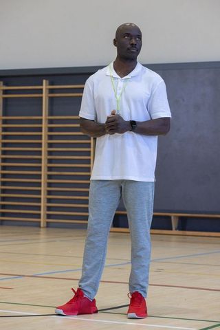 Confident coach standing in gym with activewear