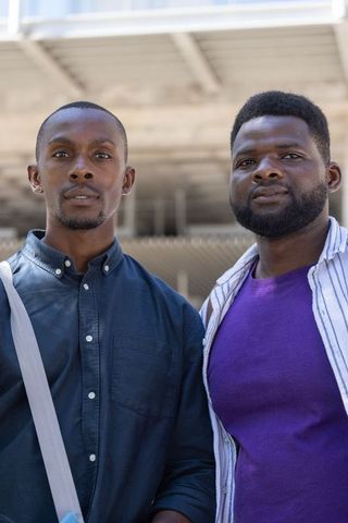 Two men standing on transit platform urban commuters casual streetstyle portrait