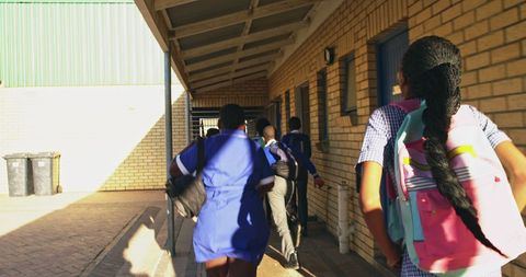 Schoolchildren walking next to building with backpacks