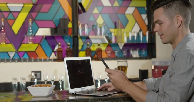 Young Man Enjoying Beverage While Using Laptop and Smartphone in Trendy Café - Download Free Stock Images Pikwizard.com